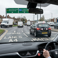Driving lesson car with 'DriveTime' branding on a road, viewed from inside another vehicle.